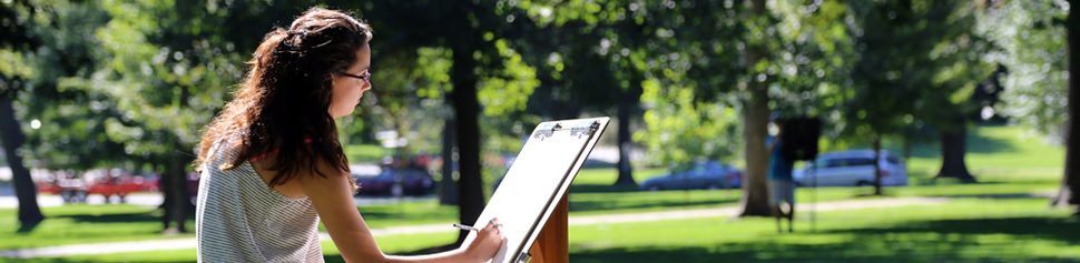 Female Student Drawing on Art Easel on Campus Front Lawn
