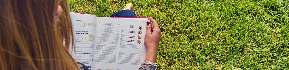 Female Student Reading Textbook on Campus Quad